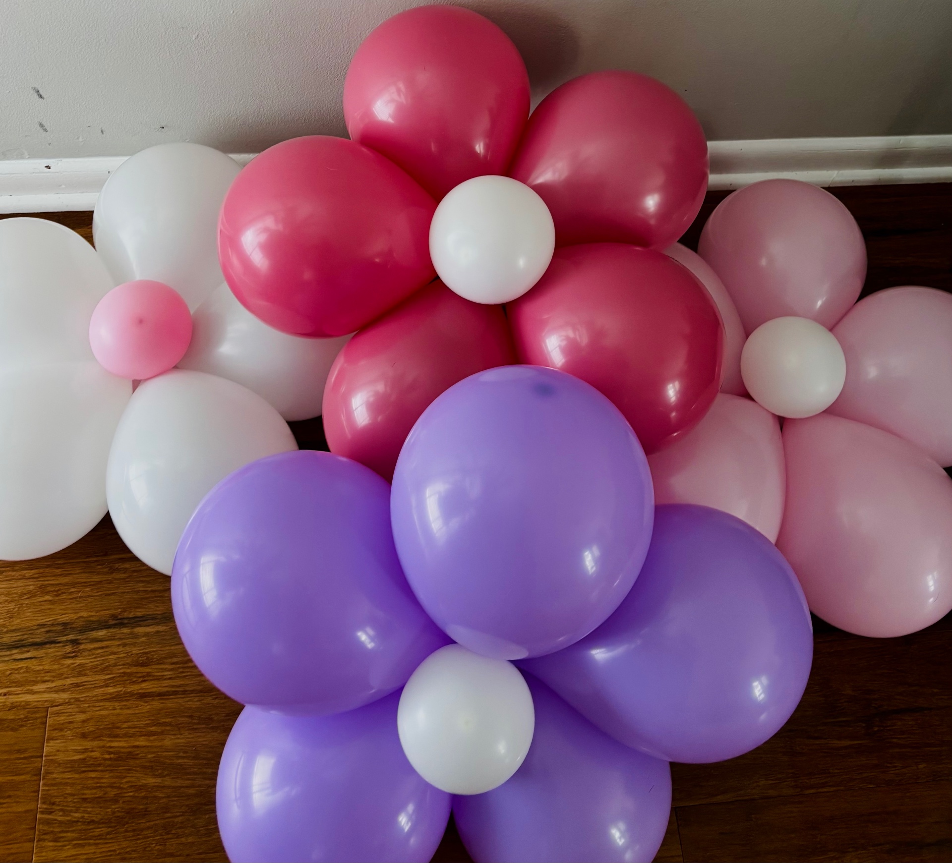 Pink, magenta, purple and white balloon flowers arranged along a wall