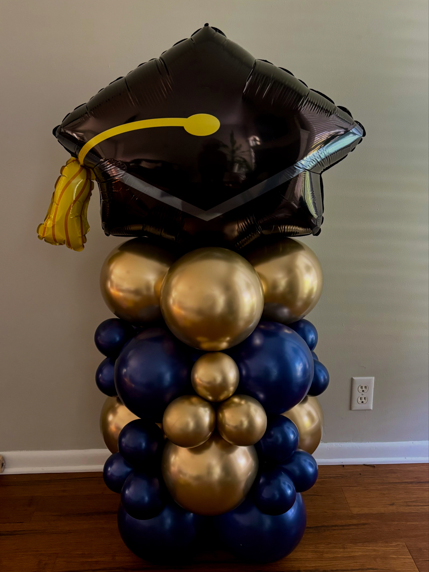 Graduation balloon column with black cap topper in navy and gold