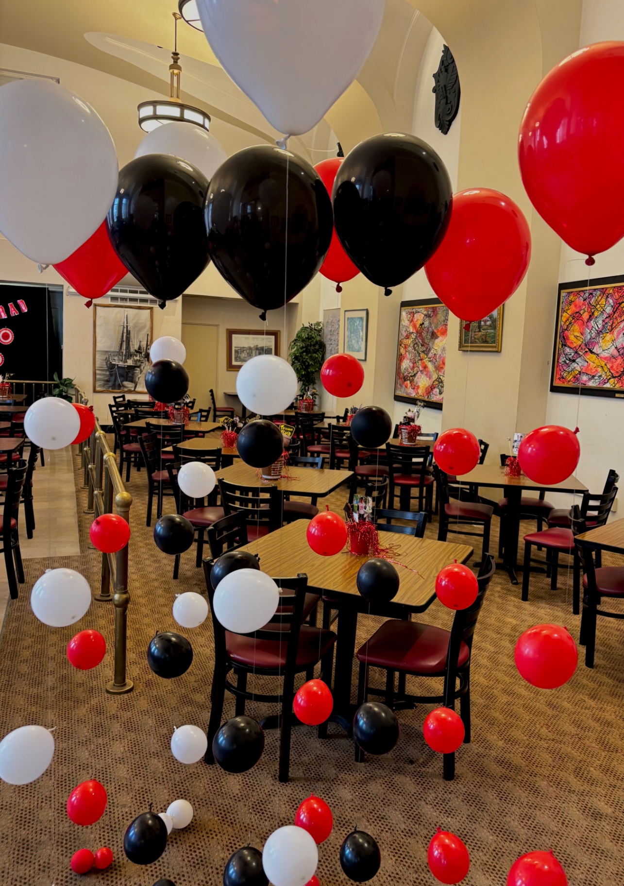 Red, black and white helium floating balloon stands in a decorated room