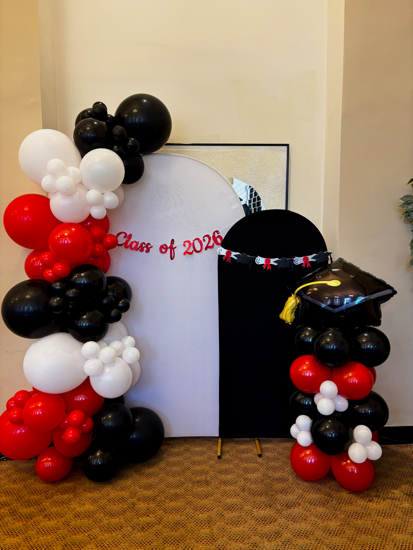 Red, black and white graduation balloon arch with Class of 2026 banner and matching column
