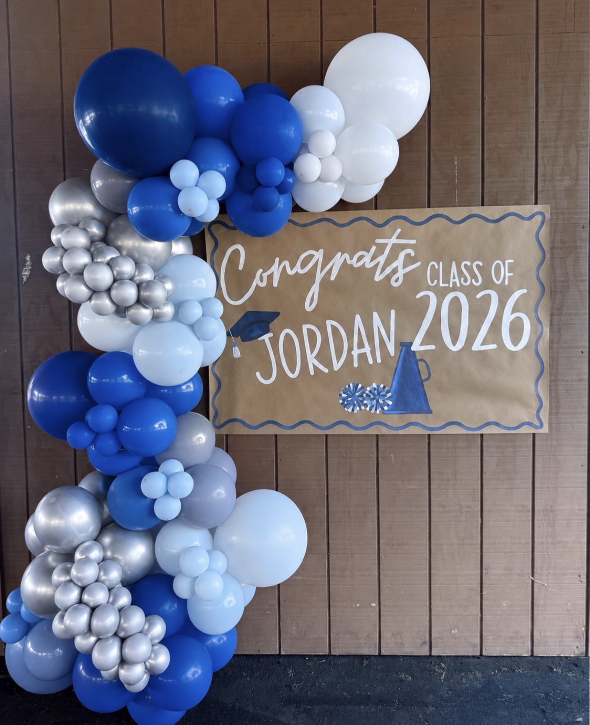 Blue, silver and white graduation balloon garland beside a custom Jordan Class of 2026 sign
