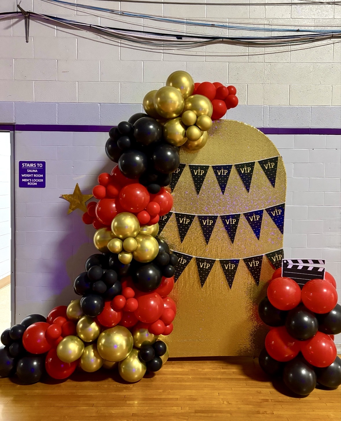 Black, gold and red balloon arch with VIP prom backdrop for a school event