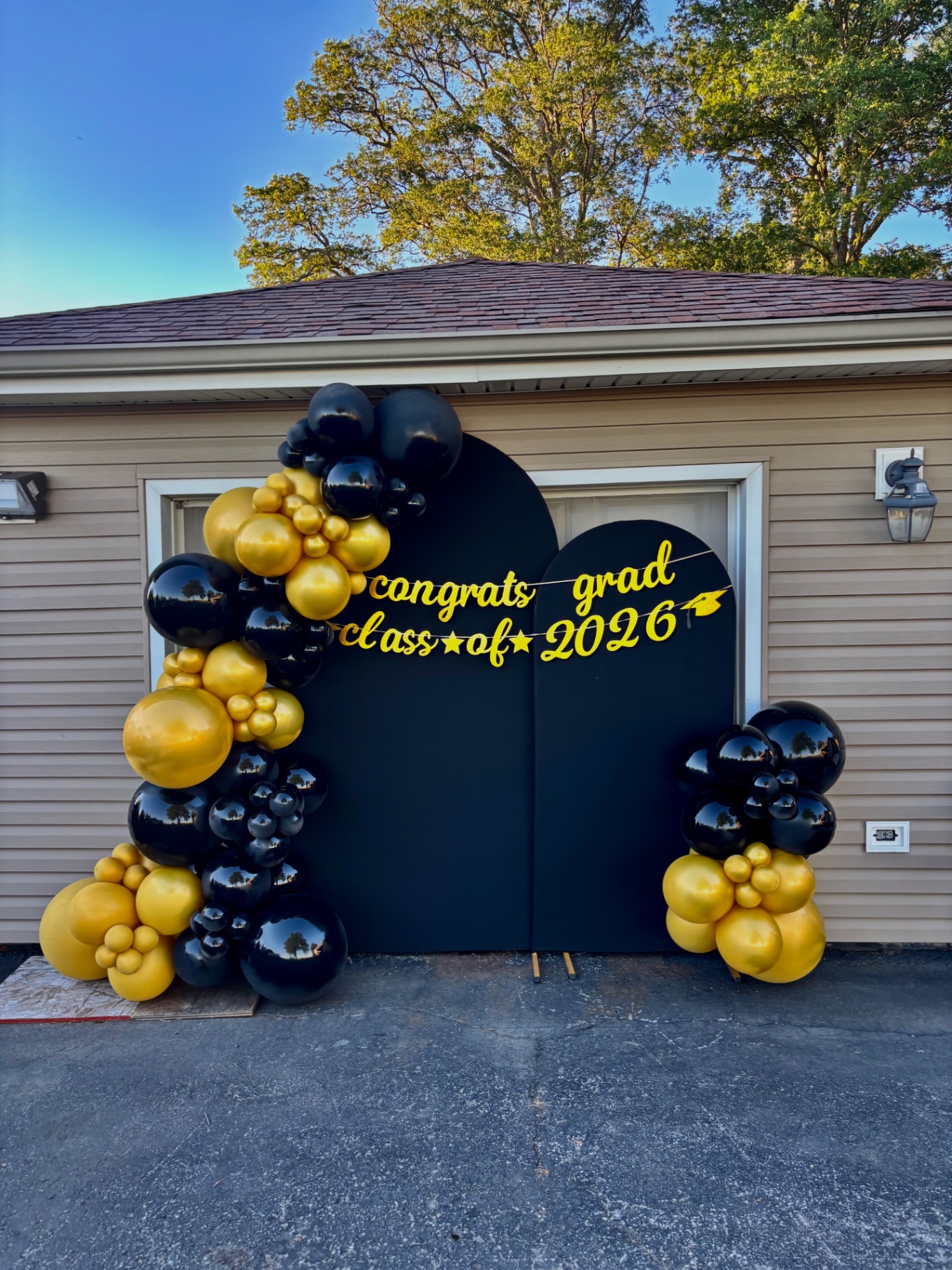 Black and gold graduation balloon arch with Congrats Grad Class of 2026 banner
